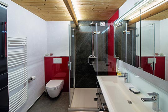 Wandhängende Toilette mit Artwall rot verkleidet, obere Abdeckung aus Mineralguss.